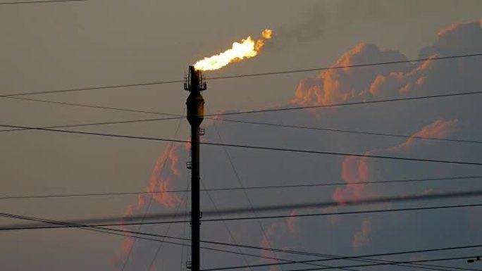 在多云的天空中，炼油厂燃烧的火炬