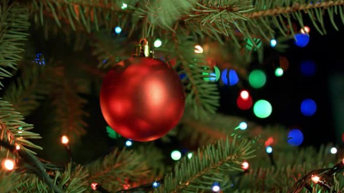 红球特写挂在圣诞树上，圣诞歌曲2017背景上的模糊灯光花环