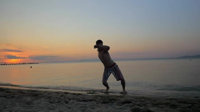 男子在日落时在海边表演杂技