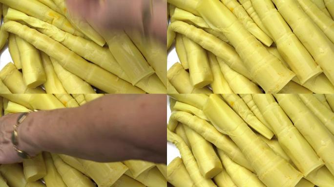 特写镜头手拿起黄色腌制的芦笋并切割。