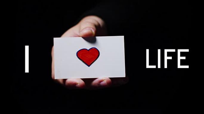 一只手展示了一张浪漫的卡片，上面写着 “我热爱生活”。理念: 爱，帮助他人，喜欢，激情，分享。热爱生
