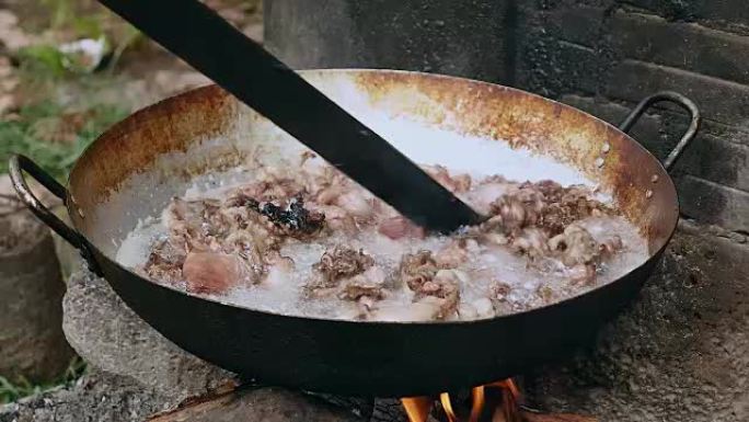 用木棍在炒锅中煎炸猪肉