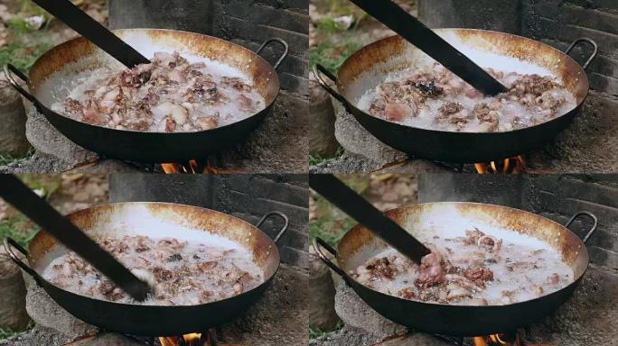 用木棍在炒锅中煎炸猪肉