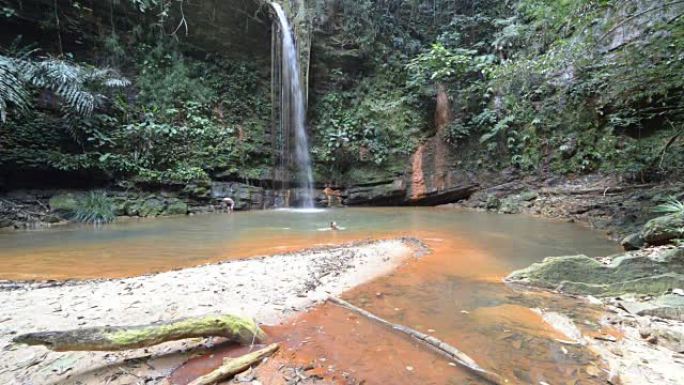 女人在马来西亚婆罗洲兰比尔山国家公园的雨林中游泳到一个迷人的五彩天然游泳池，瀑布风景秀丽。