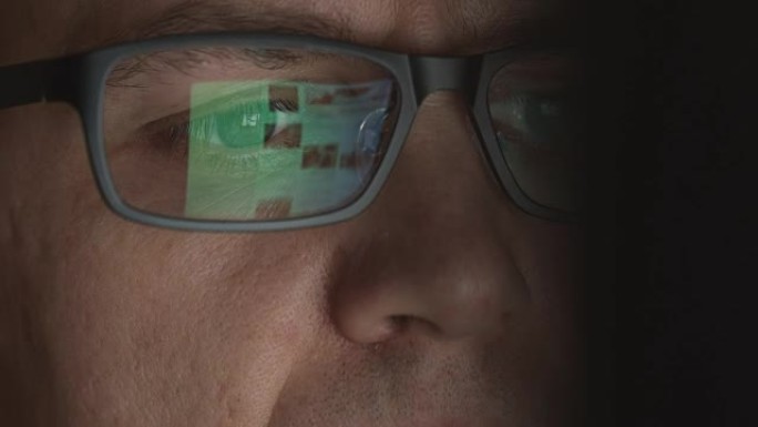在计算机上工作的成年男子的眼镜中反映滚动站点