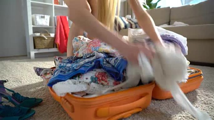 一名年轻女子随意打包，试图关闭装满橙色手提箱的行李箱。时间流逝