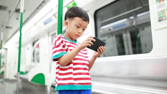 在地铁中使用智能手机的男孩