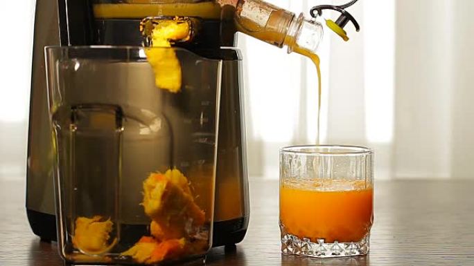 新鲜的橙汁将榨汁机倒入玻璃杯中。