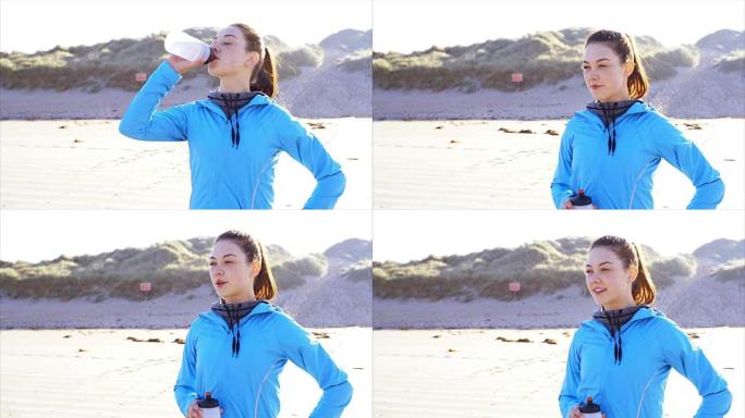 在海滩上喝水的健康女人的照片