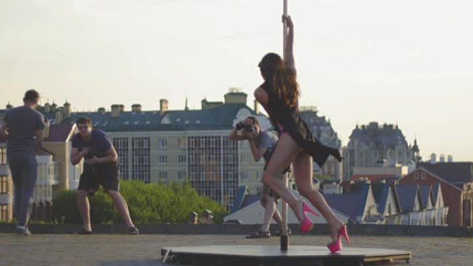 运动性感的女孩模特在自然上的杆子上为三个摄影师旋转