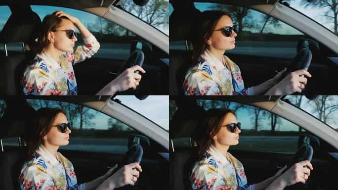 一个年轻时髦的女人戴着墨镜在开车。日落前美丽的灯光