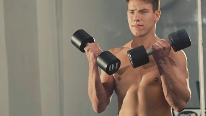 年轻的健美运动员在健身房训练手臂肌肉。慢慢地