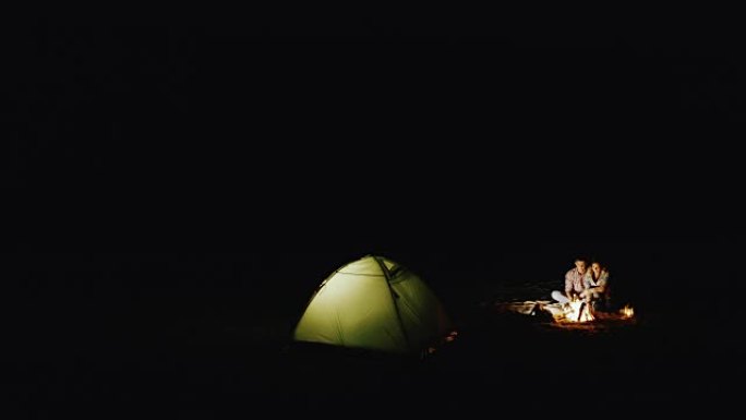 年轻夫妇在篝火和帐篷周围放松夜晚。从上方观看