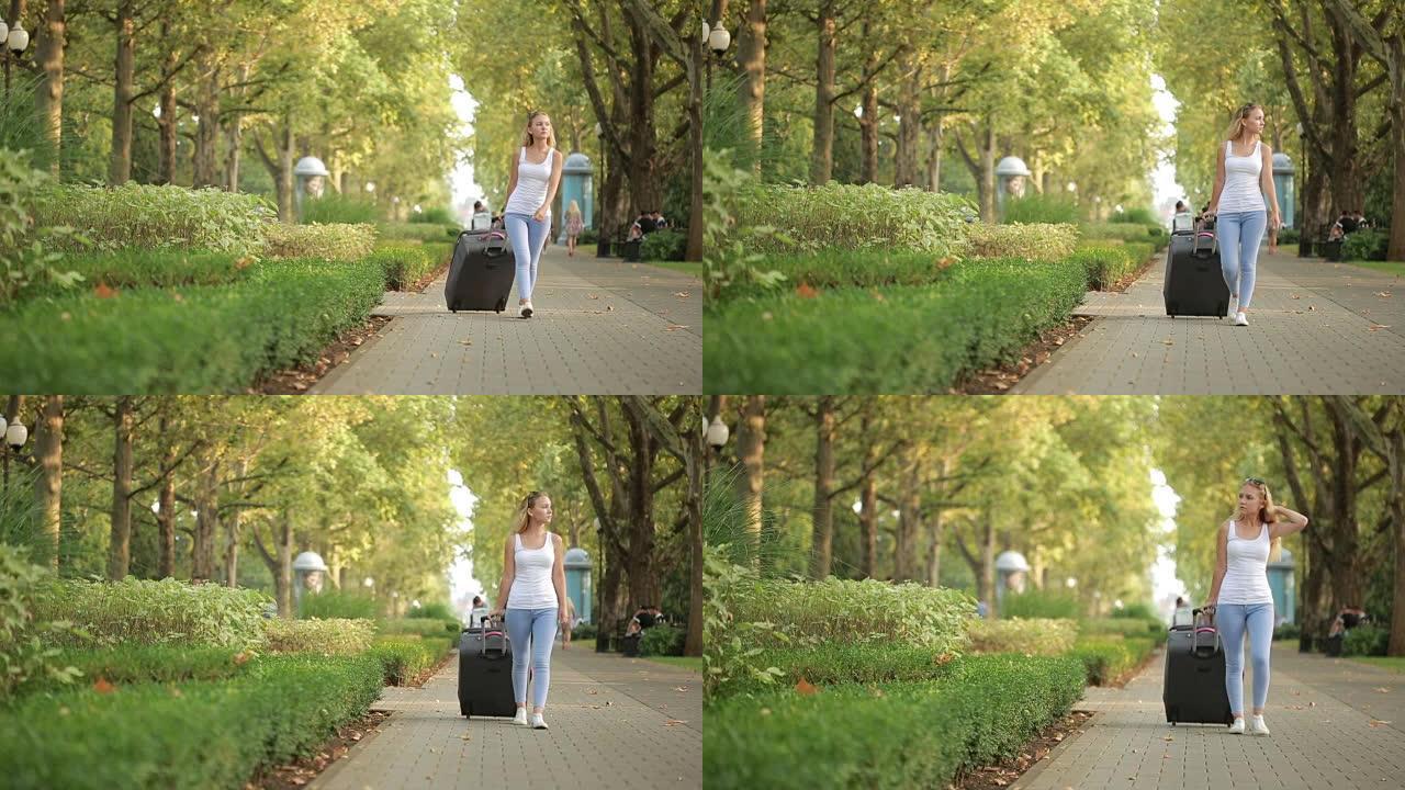 女孩带着一个手提箱沿着公园散步。