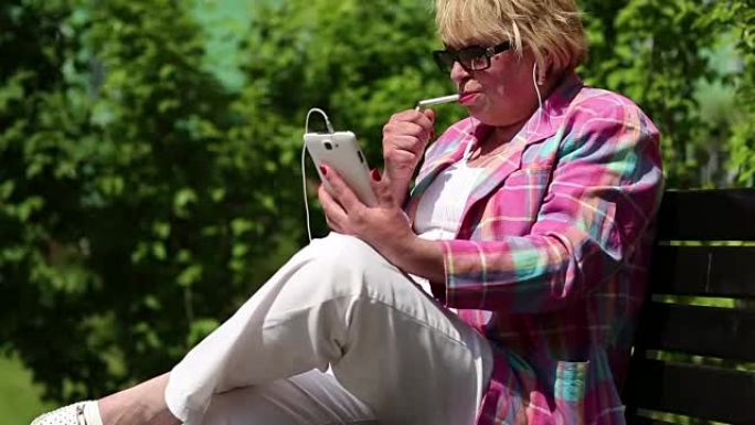 抽烟的女人坐在长凳上，通过智能手机进行交流
