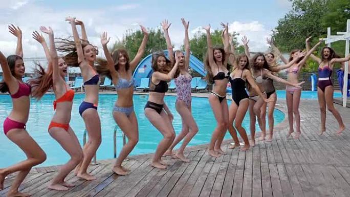 泳池派对，穿着泳衣的苗条女孩在游泳池附近跳跃，周末青年的夏季生活