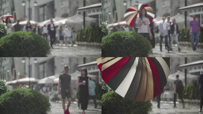 城市街道雨天的背景。实时。拿着五颜六色雨伞的年轻女孩。雨中带伞的人上下班。模糊的波克。自然背景