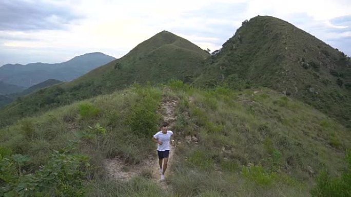 山区风景高加索人跑步男子带着一瓶水在早上慢跑。