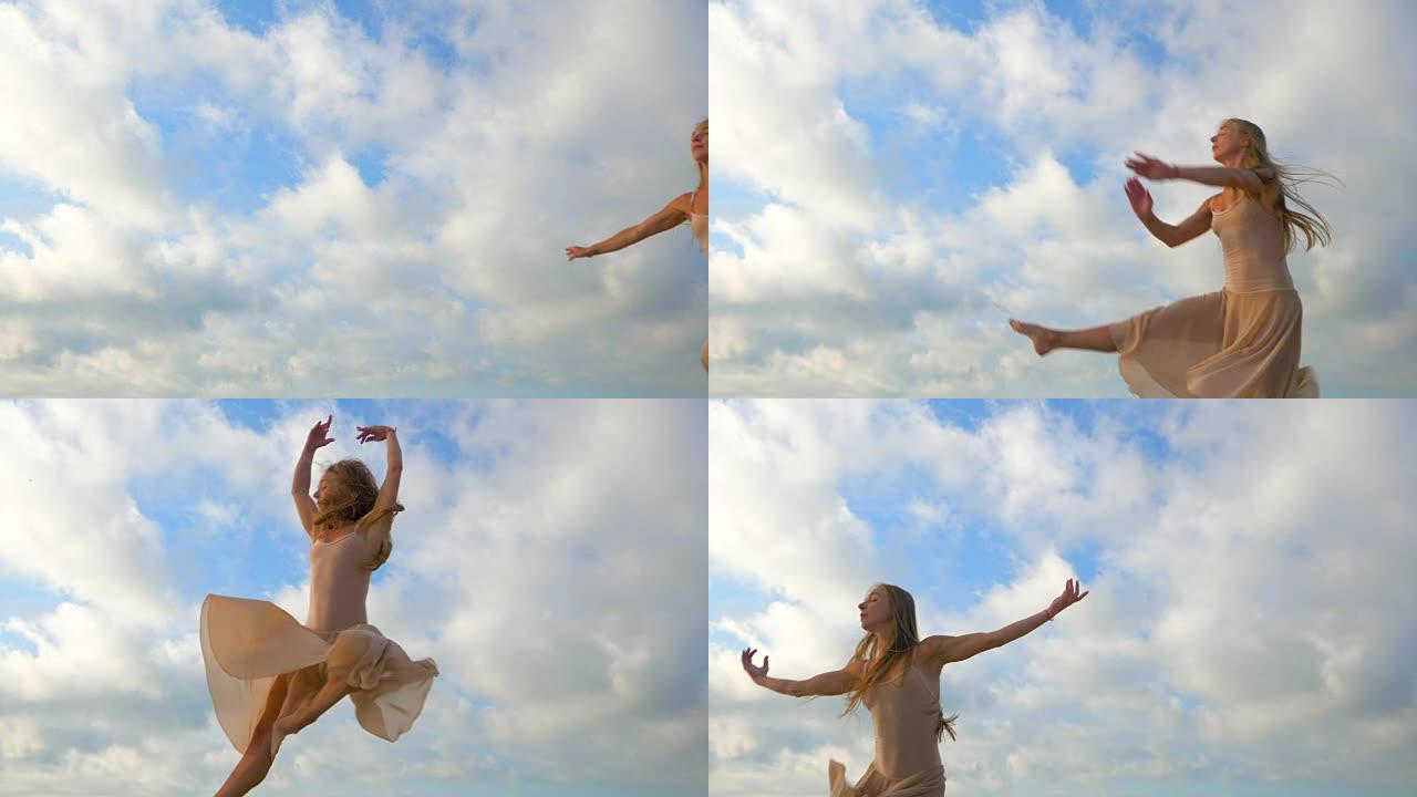穿着米色真丝连衣裙和天空背景上的尖头跳跃芭蕾舞演员。年轻美丽的金发女人的剪影，长发练习伸展和经典练习