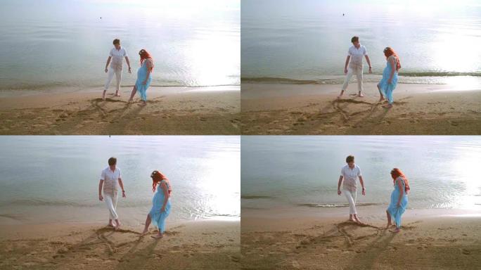 夫妇在沙滩上画心形符号。浪漫情侣在海滩上画心形