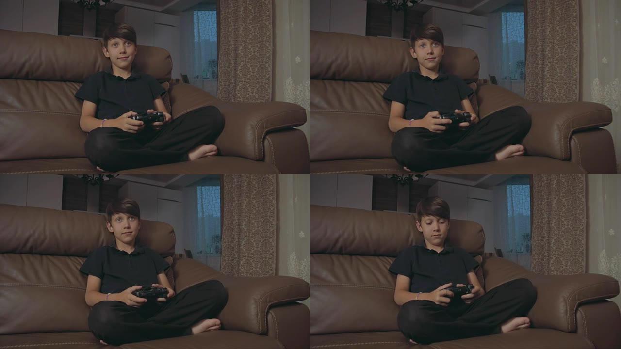 男孩在控制台上玩电子游戏在家里的沙发上