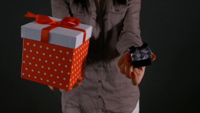 一个女人的手拿着一个大礼品盒和一个小礼品盒可供选择