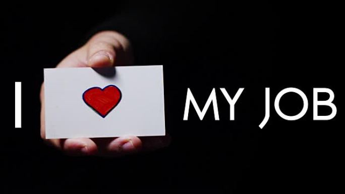 一只手展示一张浪漫的卡片，上面写着 “我爱工作”。概念: 爱，帮助他人，喜欢，热爱他们的工作，热爱他