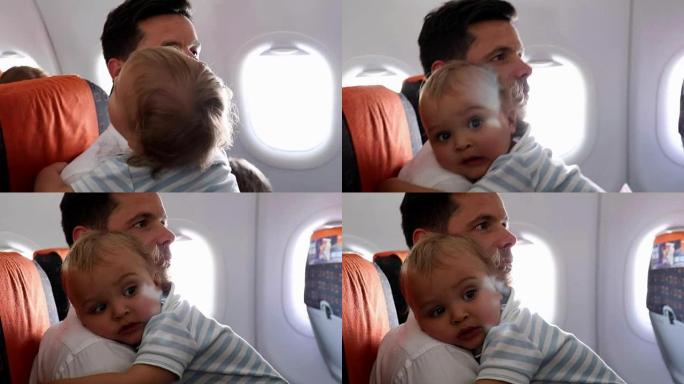 父亲把婴儿抱在飞机上。等待飞机起飞的乘客。爸爸带着婴儿乘飞机旅行