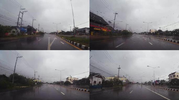 通过带有雨滴的汽车挡风玻璃的道路视图，在雨中行驶。