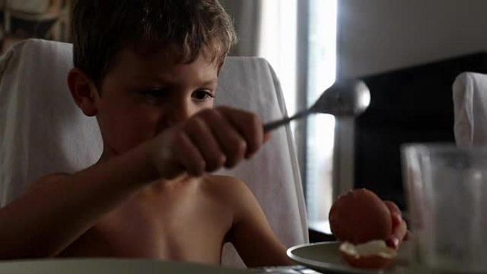 破坏性的儿童用勺子敲打桌子。被宠坏的孩子用勺子玩剩菜。年轻的6岁男孩在餐桌上制造噪音和行为混乱。