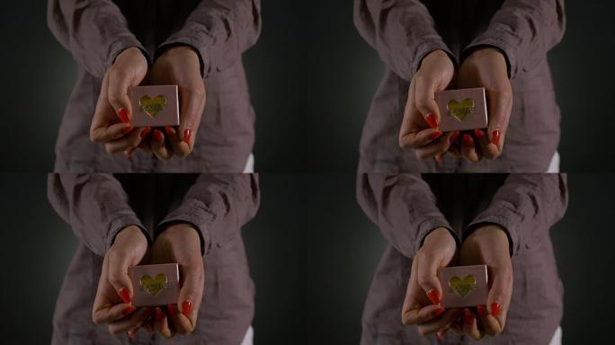一个拿着并展示小礼品盒的女人的手