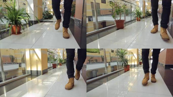 穿着棕色皮鞋的男人的腿在走廊里行走