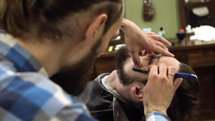专业理发师用直剃刀刮客户的胡子。非常集中。全高清