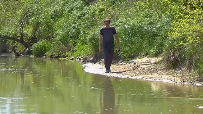 一个手里拿着钓鱼竿的人正沿着河岸行走。纺纱的家伙正在寻找钓鱼的好地方