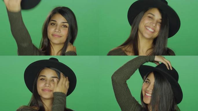 年轻女子戴着帽子，在绿屏工作室背景下嬉戏和摆姿势
