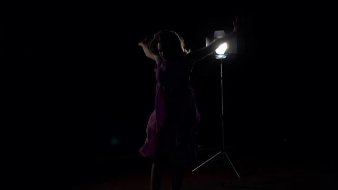 身着紫色长裙的年轻女孩在聚光灯下跳舞