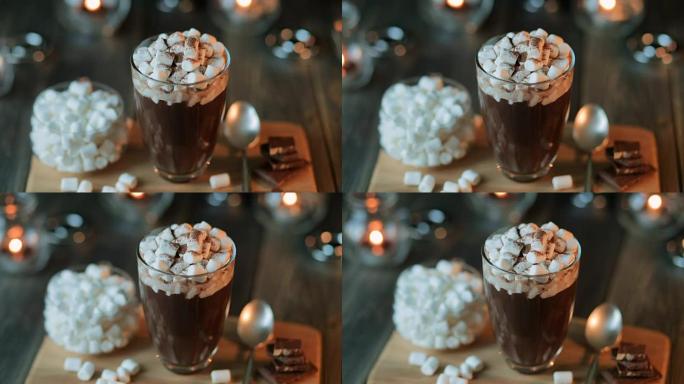 美丽的组成-热巧克力与果酱和巧克力片在一个透明的玻璃。玻璃站在木架上。蜡烛后面正在燃烧