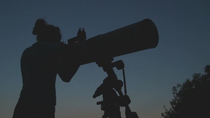 女孩在户外用望远镜看星星。