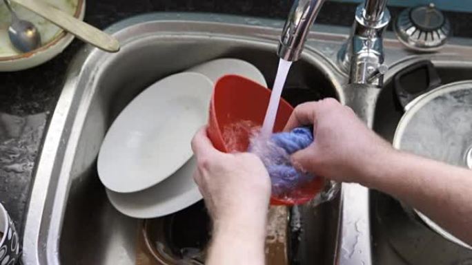 男人的手在厨房水槽里洗碗。