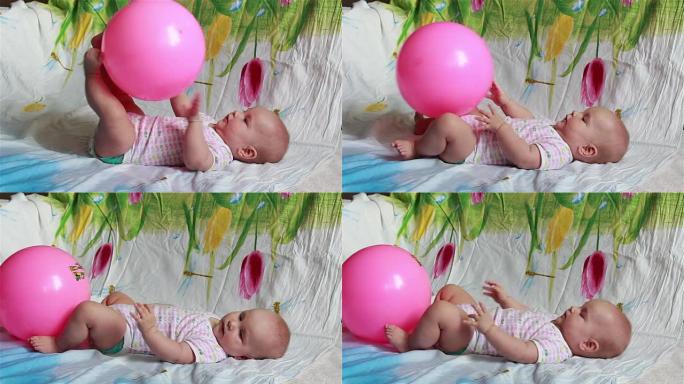 迷人的婴儿躺在床上玩一个红色的大球