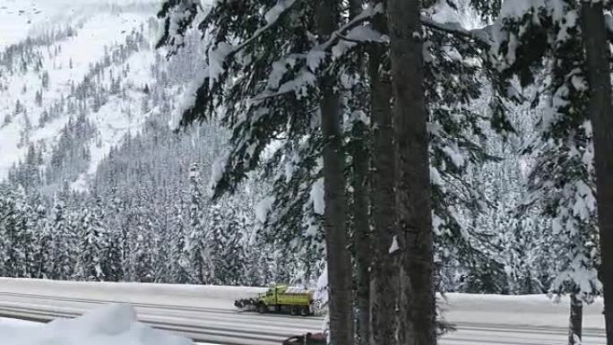 用汽车在积雪覆盖的山路上扫雪机的吊臂起重机拍摄