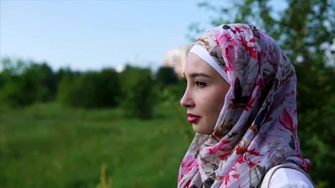 一位戴着头巾的年轻穆斯林妇女的肖像，她在公园里感到孤独