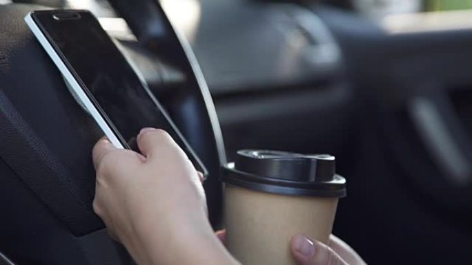 女人坐在车里用电话喝咖啡
