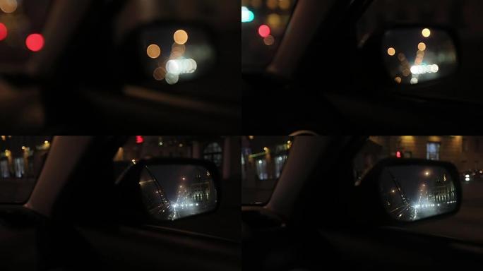 一辆车的侧镜里模糊的反光。夜晚的城市。