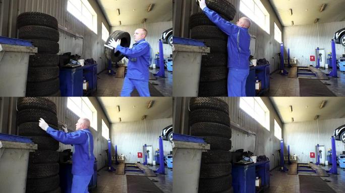 男子在车库里堆放磨损的轮胎。轮胎更换和存储服务。