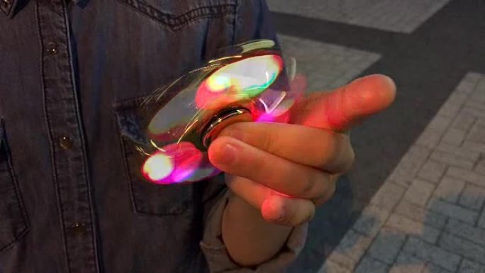 手里拿着发光的烦躁旋转器。流行时尚玩具特写。