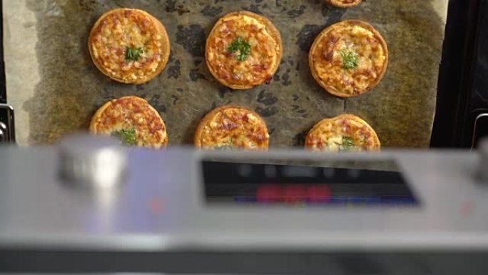 在烤箱顶视图中烹饪迷你披萨，上面放着马苏里拉奶酪和火腿
