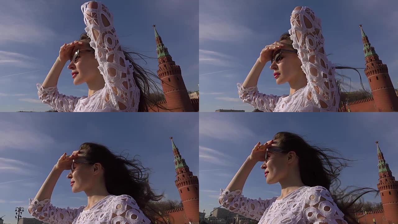 穿着白色连衣裙的年轻美女站在经过莫斯科克里姆林宫的船甲板上。全高清视频