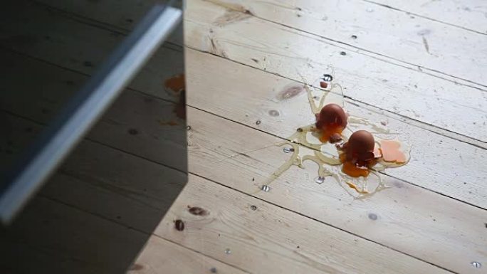 三个新鲜的棕色鸡蛋落在厨房地板上，弄得一团糟