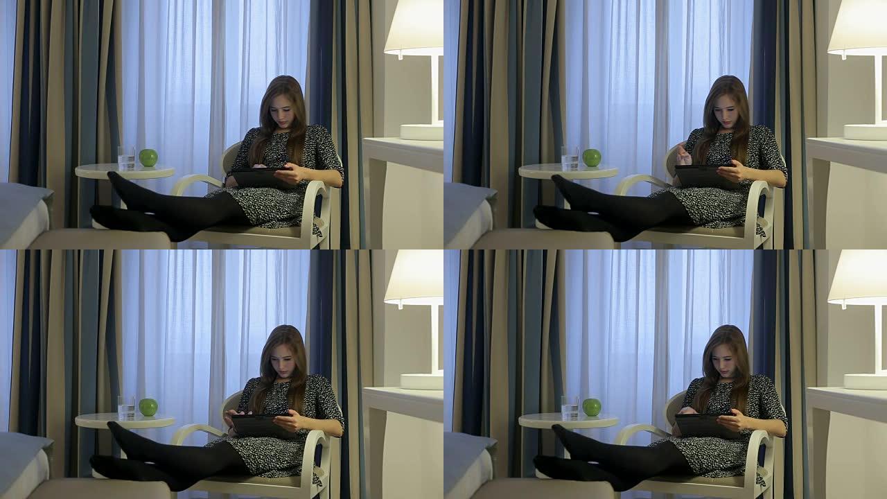 女性在互联网上通过酒店房间的数字平板电脑搜索着装